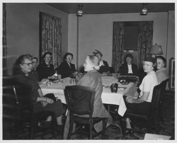 Nine women are sitting around a table. Caption reads: "Pictured above is the meeting of the Dane County Republican Women, held Thursday at 10 a.m. in the Lorraine Hotel [sic]. Mrs. Francis Lamb, chairman of the group, is seated to the left at the far end of the table. — Nell Himmelfarb."
A handwritten note reads: "Nell had her troubles again. The GOP women, she said, were very uncooperative."