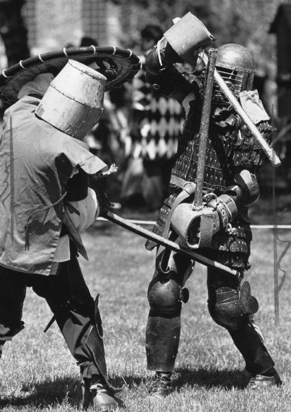Two people in armor battling with practice swords. Caption reads: "KNIGHTS OF OLD — Eric Chance (left) and Scott Hall engaged in battle as they fought to be "King" at the Spring Crown Tournament of the Society of Creative Anachronism Sunday in Racine. The group gathered for arts and science championships, as well as jousting and a medieval banquet. The group re-creates English society from the years 600 to 1600."