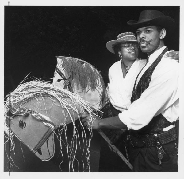 A man and a woman posing together. Both are wearing cowboy/cowgirl costumes and riding hobby horses. Caption reads: "With the Old West as the theme, family members Sandra Thomas and Derek Jeter rode in for the reunion on their hobby horses."