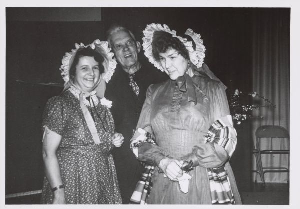 Two women in historical dress posing with a man. Caption reads: "Left to right: Dorothy Sohns an Ephraim Wis school teacher Hjalmar Holand * and Mrs. Olga Dana during the Ephraim Wis Centennial celebration May 18 1953" and "*Mr Holands [sic] granddaughter won a Rennebohm award for her story of Mr Holand published in the March 1957 issue of <u>Badger History</u>".