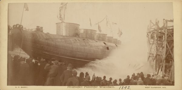 Launching Captain Abe McDougall's passenger whaleback boat,"Christopher Columbus", from the American Steel Barge Company dock. Text at bottom right of card reads: "West Superior Wis."
