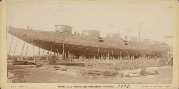 Whaleback steamer under construction in the American Steel Barge Company shipyard in Superior, Wisconsin. Text at bottom of card reads: "McDougall Passenger Whaleback Steamer. West Superior, Wis."
