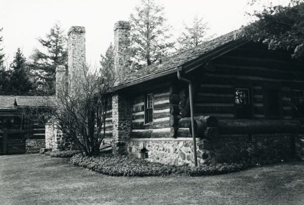 The back and side of the main lodge at Forest Lodge on Lake Namakagon. The lodge was re-built in 1914-15 and remodeled in 1928-29. It is a single-story horizontal chinked log house with a stone foundation, cedar shake roof, and three large stone chimneys.