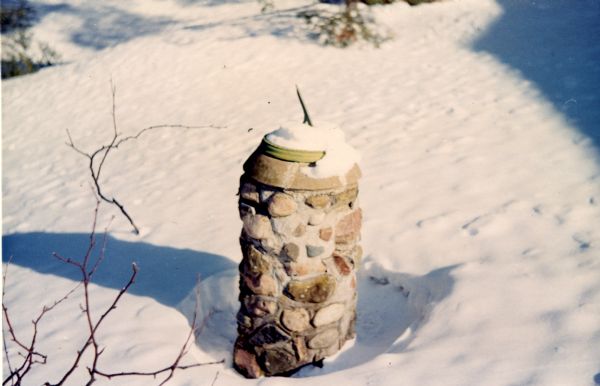 A circular stone and cement sundial in a snowy yard.