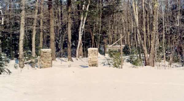 Wrought iron gate suspended on two stone gate posts.