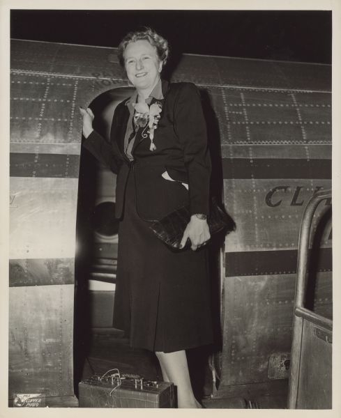 Typed note with photograph reads: "Pan American World Airways Photo, To Write on Tension in Germany, Miss Esther Van Wagoner Tufty, Washington newspaper correspondent, lecturer and radio commentator, is shown leaving La Guardia Field on a Pan American World Airways Clipper for a two month trip to Germany, Austria and the Netherlands. She has been invited to the coronation of Princess Juliana in September and her itinerary includes a two week stay at Hitler's retreat at Berchtesgaden in the Barvarian [<i>sic</i>] Alps. Her writings on todays tense situation in Germany will be serviced by the Tufty News Bureau in Washington, D.C. From Pan American World Airways, La Guardia Field, N.Y."