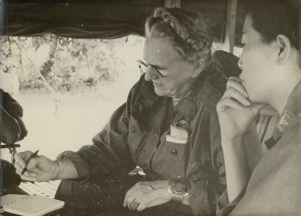 American journalist Esther Van Wagoner Tufty, who covered three wars, taking notes on an interview with Major Kim Pil Dal, a Korean nurse in Vietnam. Caption reads: "Major Kim, Pil Dal, chief nurse officer, 6th ROK Evac Hospital, explains how to treat wounded soldiers since her arrival in Vietnam October 1965. (Oct. 11, 1966)".