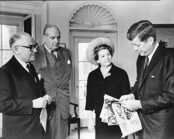 President John Kennedy looking over the Great Decisions Fact Sheet Kit in the Oval Office with representatives of the Foreign Policy Association, (FPA). From left to right: Emile E. Soubry, Walter H. Wheeler, Jr., Mrs. Albert Greenfield and President Kennedy.