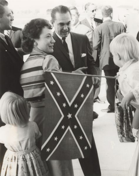 Supporters greet Alabama Governor George Wallace during a Presidential primary campaign stop in Oshkosh. A supporter in the foreground (out of frame) is holding a baby and a Confederate flag.