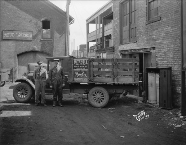 Mitchell Sales Co. delivery truck, with two men making a delivery to the rear of a store, Pyrofax agent.