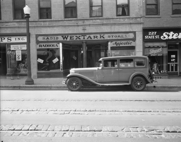 View across street towards the Capital Times car in front of Wextark store, 225 State Street. Stewart Smart Shop is on the right.