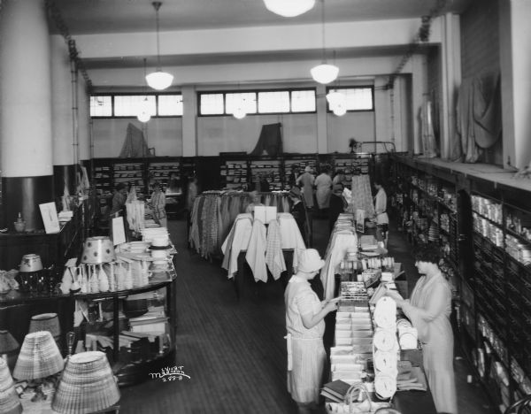 Elevated view of Kessenich's Silk Department, 201 State Street. Two women are standing on either side of a counter in the right foreground.