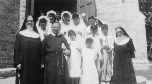 Catholic clergymen and nuns pose with a group of migrant children on the event of their first communion.