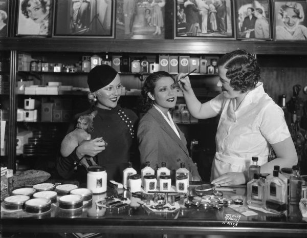 Raquel Torres at Manchesters cosmetics counter with Max Factor representative, Mabelle Hege, and another woman holding a dog.