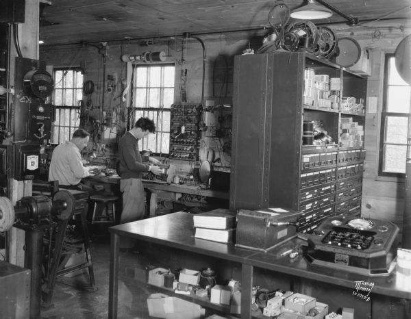 Right interior of Kidder Radio Shop, 113 N. Baldwin Street. Shows two men working on radios.