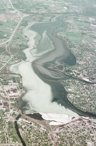 Aerial view titled "Neenah Pollution." The view is looking north from over Neenah at Little Lake Butte des Morts which is discolored.