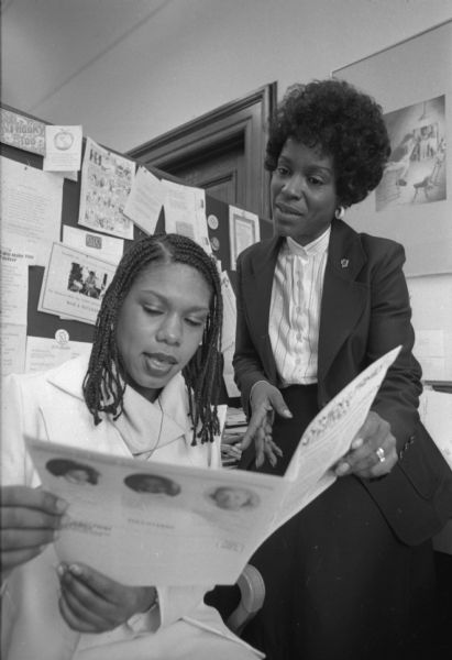 Marlene Cummings, Special Advisor for Women's initiatives for Governor Lee Dreyfus, at right, in an office looking over a newsletter on women's initiatives and family affairs with Sylvia Dunnavant, a UW-Madison student who works for her. 