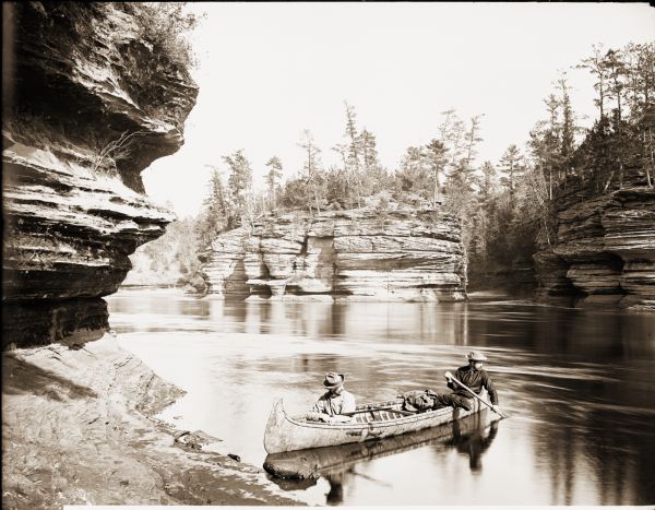 Opposite Steamboat Rock. Two men are in a canoe near the shore in the foreground.