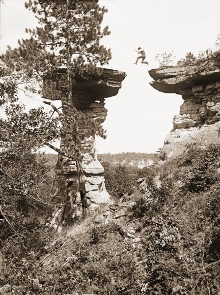 Ashley Bennett, son of photographer H.H. Bennett, is captured in mid-air as he jumps to Stand Rock.