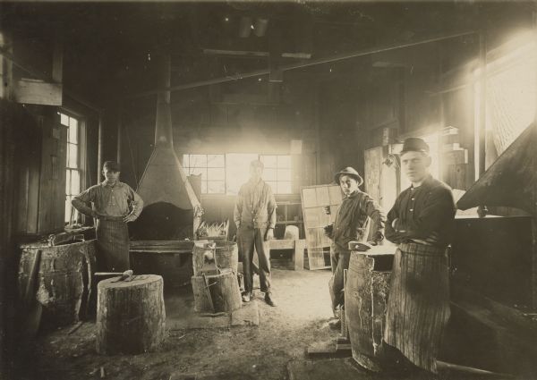 Four men are posing inside the blacksmith shop at Montello Granite Co.