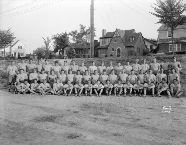Outdoor group portrait of the West High School football squad in uniform. Also shows houses at 1 S. Vista, 2301 Regent, 2305 Regent and 2309 Regent Street.