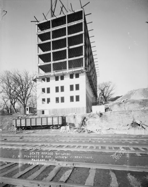 View across railroad tracks towards the State Office Building, 1 W. Wilson Street, under construction.
