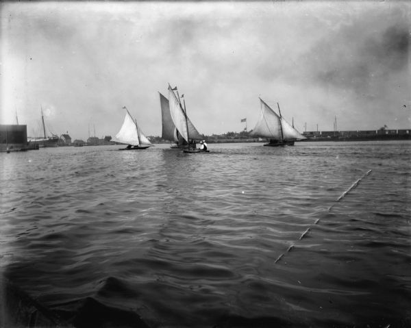 Four sailboats in Milwaukee Harbor, one of which, <i>The Kim</i>, has Syl on board. In the background are railroad cars and industrial buildings.