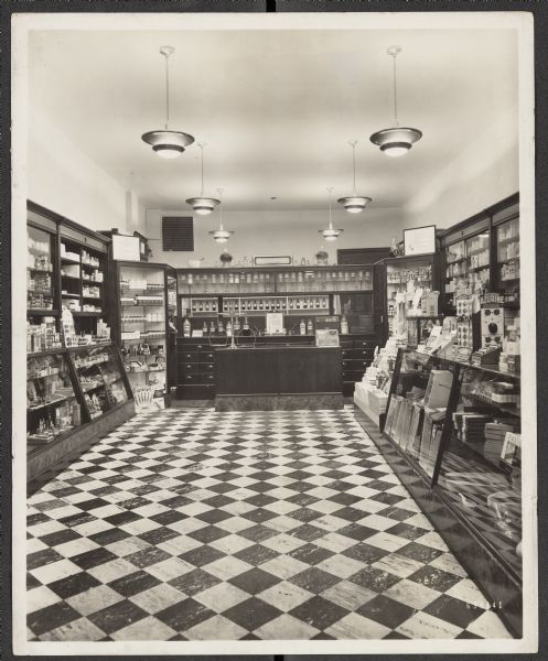 Many toiletries, medicines, and sundries fill the cabinets on both sides of Hieber's Drugstore. Traditional glass label bottles line the back wall behind the cash register and prescription counter.
