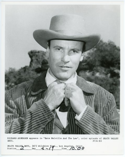 Richard Anderson portrays Judge Lander in the episode "Kate Melville And The Law" of the TV show <i>Death Valley Days</i>.  Anderson wears a hat and suit and is adjusting his tie while looking directly at the camera.