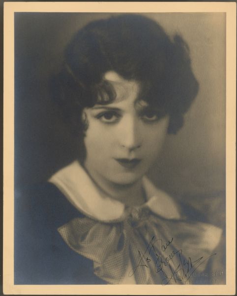 Actress Helen Ferguson looks straight at the camera in a publicity photograph.  She is wearing a top or dress with a very large bow.  A handwritten inscription at the lower right reads: To Dave from Helen.