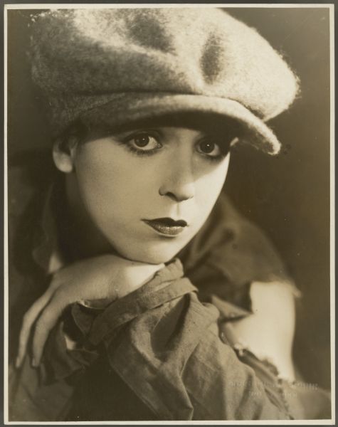 Closeup photograph of actress Helen Ferguson in costume for the stage play <i>The Alarm Clock</i>.  She is wearing a pageboy cap and tattered coat.