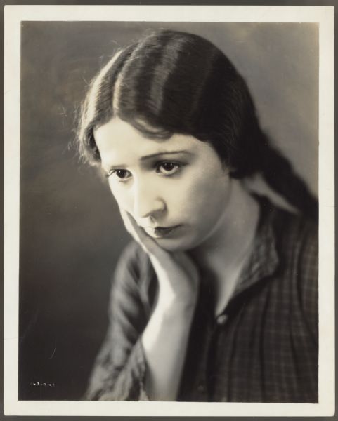 Publicity photograph of actress Helen Ferguson for the 1922 film <i>Hungry Hearts</i>.  Her hair is straight and she has one hand up to her chin.  She looks downcast.