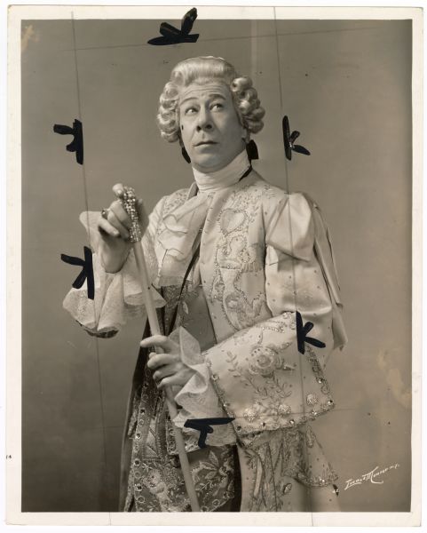 Actor Bert Lahr poses for a publicity photograph for the musical <i>Du Barry Was a Lady</i>.  Lahr is dressed as King Louis XV of France.  He has a powdered wig on and holds a walking cane with a bejeweled top.